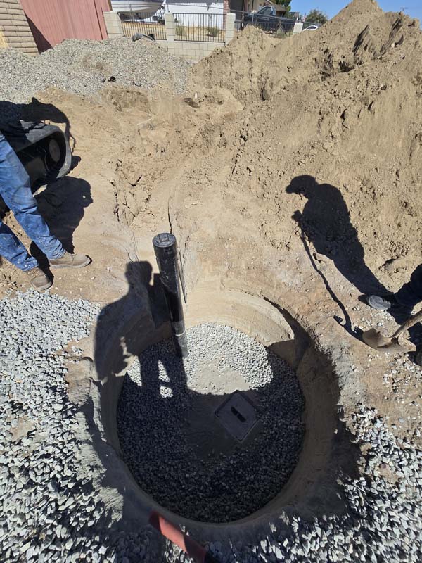 Concrete-lined seepage pit with gravel at the bottom during septic system installation in Victorville